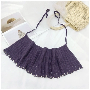 Détail du châle en tricot violet avec bordure élégante ornée de perles blanches fines