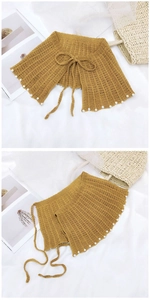 Détail du châle tricoté jaune moutarde avec perles blanches et ruban décoratif chic
