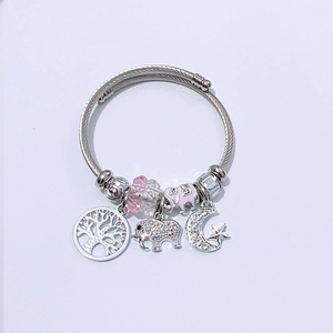 Detail view of silver steel cable bracelet with pink charms and life tree pendant