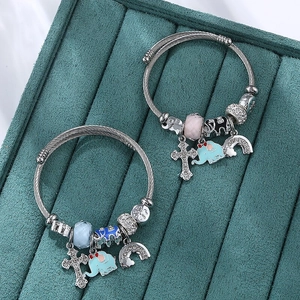 Beaded stainless steel bracelets with elephant, cross, and rainbow charms on velvet