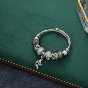 Beaded charm bracelet with hollow leaf pendant and silver metallic beads on display