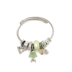 Silver beaded charm bracelet with green crystal fish and heart pendants on white background