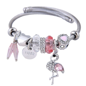 Bracciale argentato con ciondolo fenicottero e perle di cristallo rosa su sfondo bianco