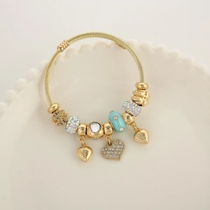 Bracelet câble doré réglable avec breloques cœur et perles bleues sur plateau blanc