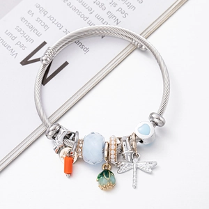 Beaded charm bracelet with blue dragonfly and floral pendants on silver steel cable band