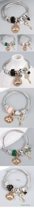Detail of adjustable charm bracelet featuring enamel bee pendants and crystal heart keys