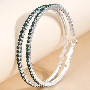 Close-up of silver-tone hoop earrings with sparkling green rhinestone pave detailing