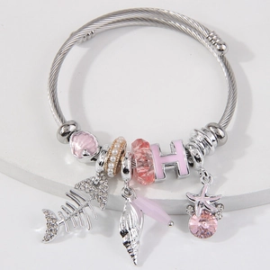Silver charm bracelet with pink fishbone, starfish, and seashell pendants on white stone