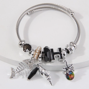 Twisted stainless steel bracelet with fishbone, shell, star, and pearl charms on stone tray