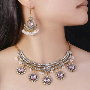 Ethnic gold jewelry set featuring pink crystal stones and white pearl tassels