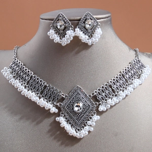 Vintage ethnic jewelry set with silver necklace and pearl drop earrings on display