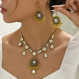 Bohemian gold jewelry set with green crystals and metal tassels worn by a model