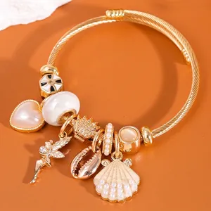 Goldenes Bettelarmband mit Muscheln und Herzperlen auf orangefarbenem Hintergrund