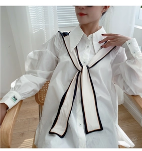 Detail of white cotton shirt featuring a navy collar with contrast edging and lantern sleeves