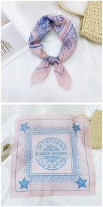 Macro detail of a pink cotton linen square scarf with blue star patterns and lettering