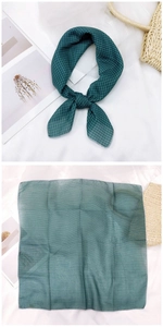 Detail of dark green gingham square scarf shown tied as a bow and laid flat on fabric