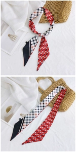 Détail d'un foulard étroit à carreaux et fleurs noué sur un sac en paille