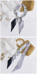 Détail d'un foulard étroit en soie avec motif à carreaux et imprimé marguerites