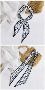 Détail d'un foulard en soie à imprimé géométrique noir et blanc noué en nœud élégant