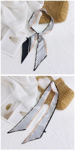 Détail d'une écharpe longue en soie pied-de-poule avec bordure orange sur sac