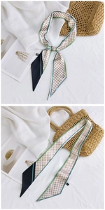 Détail d'un foulard étroit à carreaux avec bordure verte et bloc noir dans un décor lumineux