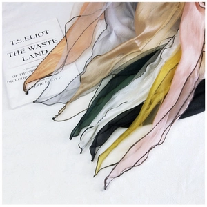 Detail view of multi-color sheer chiffon scarves with decorative black wavy stitched edges