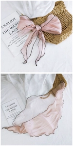 Close-up of pink mesh scarf with black wavy edges and semi-transparent texture