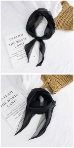 Detail shot of lightweight black sheer mesh scarf showing texture and drape over books