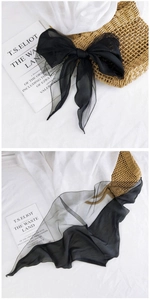 Detail of sheer black diamond mesh scarf tied in a bow with light transparent texture