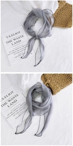 Detail of grey sheer mesh scarf with black hem showing lightweight texture and drape