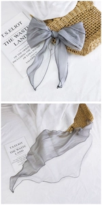 Macro detail of a grey sheer organza scarf with black stitched edges on a white fabric