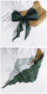 Detail of dark green organza bow scarf with translucent texture and wavy edges