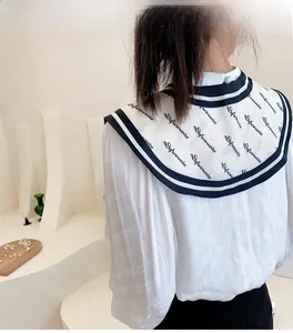 Detail of white sailor collar with navy stripes and lettering on a textured shirt