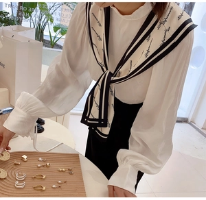 Detailed view of white chiffon shirt with striped sailor collar and elegant bow detail