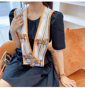 Detail of silk scarf with classic horse print and stripes layered over a black dress