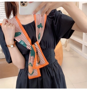 Detail of owl-patterned houndstooth silk scarf on black dress with orange piping