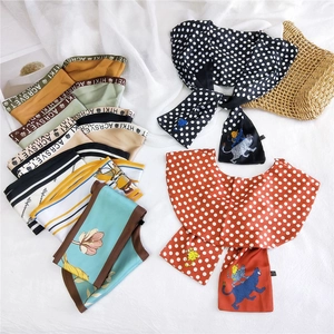 Flat lay of colorful double-layered silk scarves with floral and polka dot patterns
