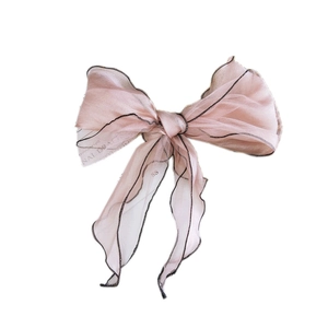 Pink organza bow hair accessory with black trim and elegant long streamers on white base