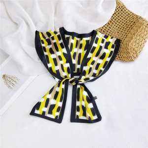 Close-up of a double-layered silk scarf with yellow and black abstract dot patterns