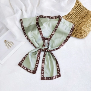 Detail of light green silk scarf with brown floral borders and elegant printed lettering