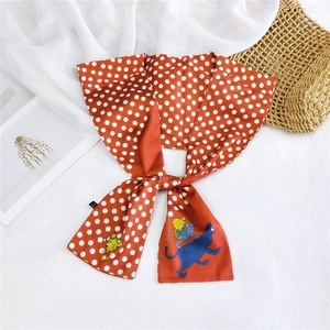 Detail of orange polka dot silk scarf featuring cute cat illustrations on white fabric