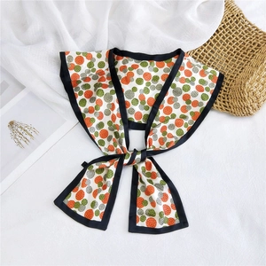 Detail of silk-like scarf with orange and green polka dots on a white textured background