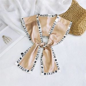 Detail of silk scarf with rose print and elegant lettering on champagne fabric