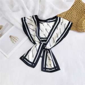 Detailed view of an elegant cream silk scarf tied in a bow with black floral lettering