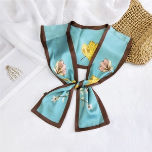 Detail of light blue silk scarf with tulip floral print and brown trim on textured fabric
