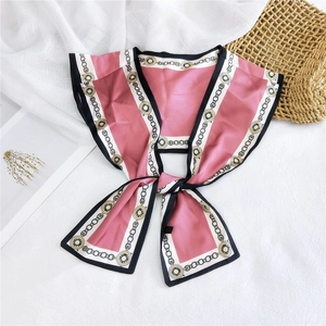 Detail of pink silk scarf with geometric chain patterns and black rolled edges on fabric