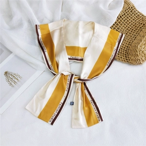Detail of yellow striped silk scarf with Fashion Studio print on white linen background