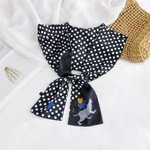 Close-up of black and white polka dot silk scarf featuring a cute cat illustration