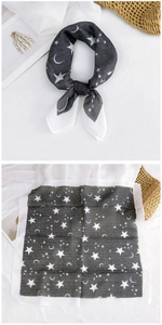 Detail of black and white star and moon pattern neck scarf on a textured background