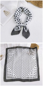 Detail of a square silk scarf with black polka dots, hearts, and wide grey borders
